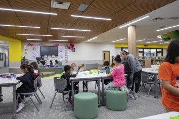 Students collaborate while a teacher assists others